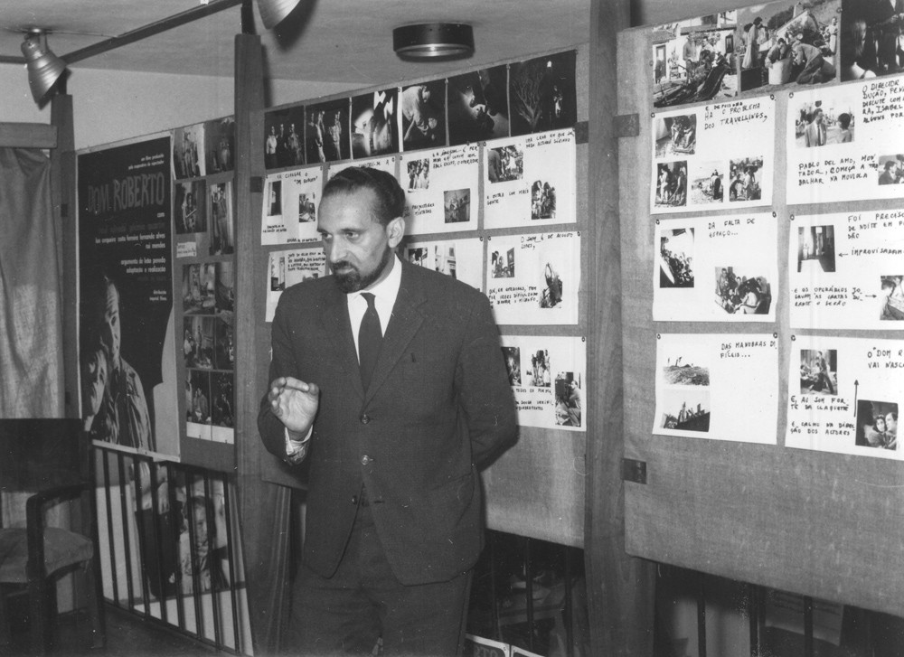  Ernesto de Sousa numa sessão de divulgação de Dom Roberto, c. 1962. No fundo, o cartaz e cenas do filme. 